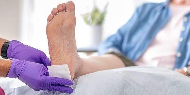 Infirmière appliquant un pansement sur le talon du patient
