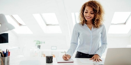 Femme écrivant des notes dans un bureau
