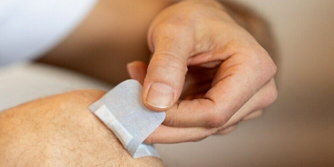 Homme en train de décoller le pansement Nexcare™
