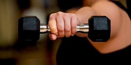 Pansement Active Tape sur le doigt de la personne qui soulève l’haltère
